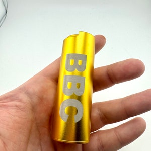May include: A gold-coloured metal tube with the word "BBC" engraved in white lettering.