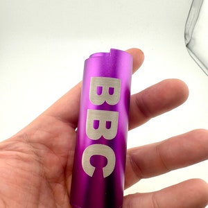 May include: A purple metal lighter with the word "BBC" engraved on the side.