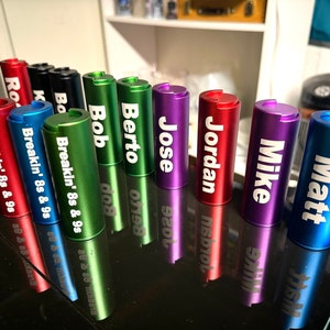 May include: A row of ten colorful metal containers with different names engraved on them, including "Matt", "Mike", "Jordan", "Jose", "Berto", "Bob", "Breakin' 8s & 9s", and "Ro".