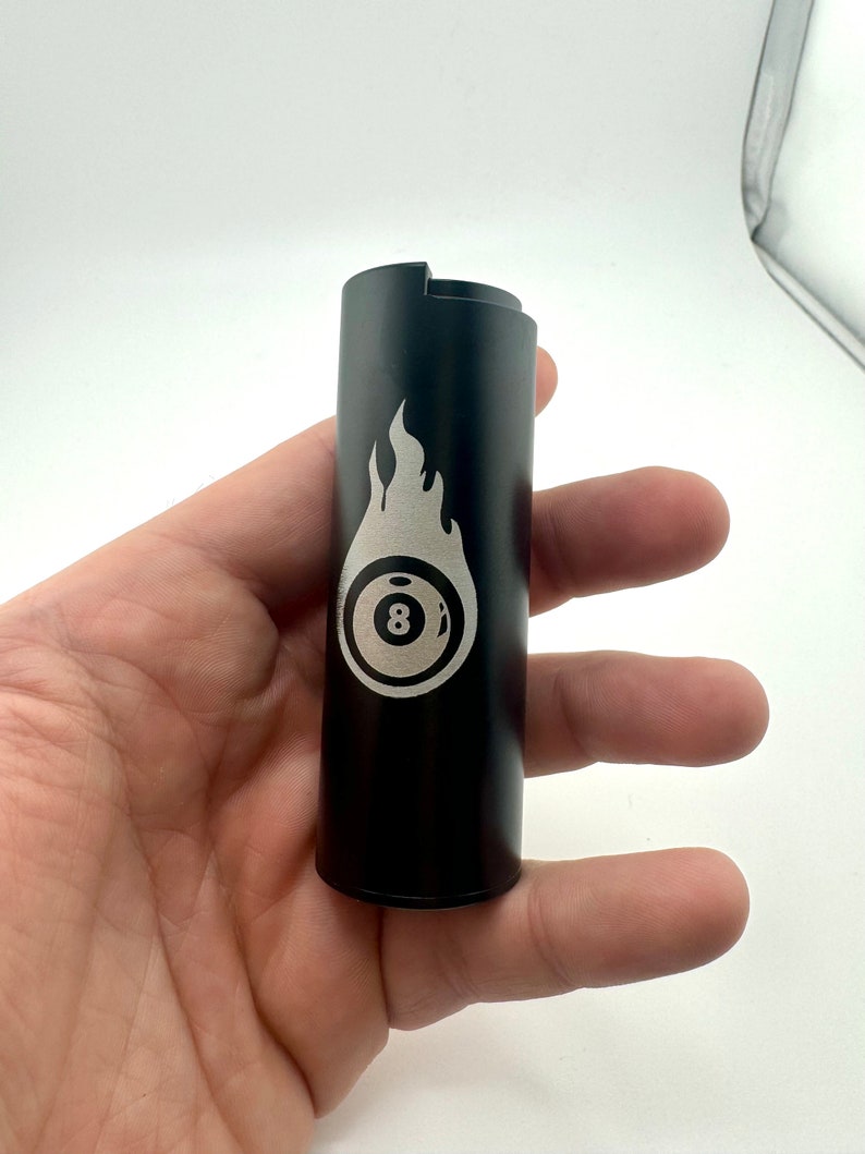 May include: Black metal lighter with a silver 8-ball and flame design.