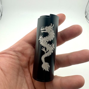 May include: Black metal lighter with a silver dragon design engraved on the side.