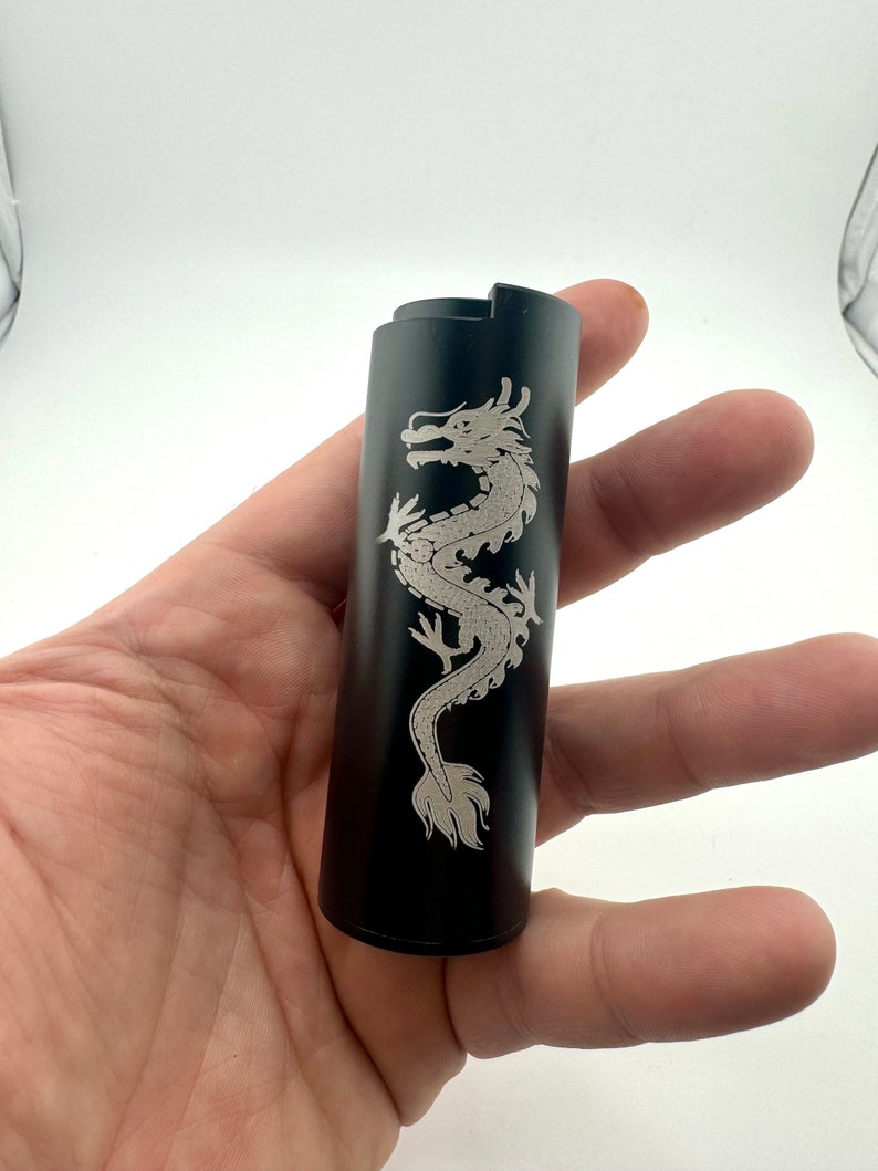 May include: Black metal lighter with a silver dragon design engraved on the side.