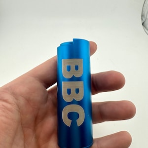 May include: A blue metal tube with the word "BBC" engraved in silver lettering.