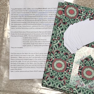 May include: A quilting kit containing a printed instruction sheet about Lucy M. Boston, a piece of fabric with a green, black, and pink floral pattern, and a stack of white paper honeycomb templates for English paper piecing projects.