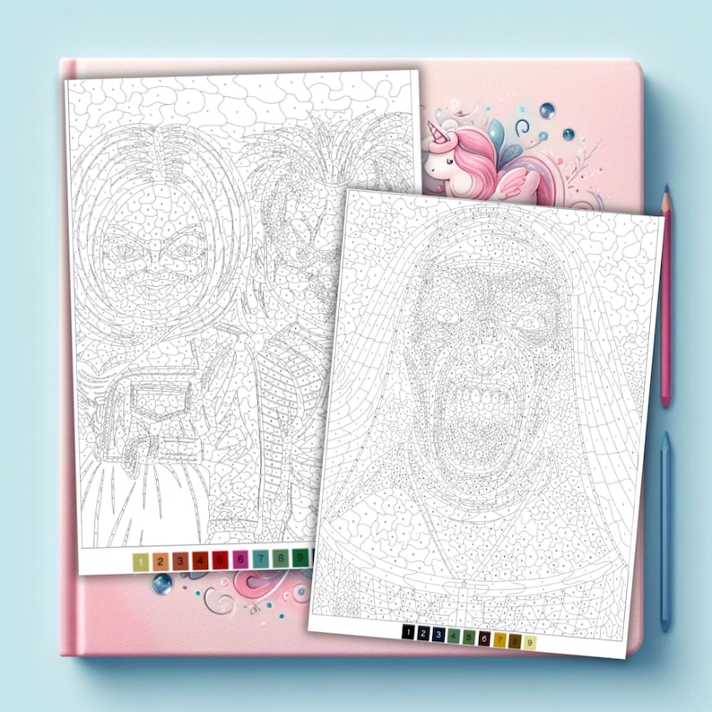 Puede incluir: Dos hojas de pintura por n&uacute;meros con personajes de terror, incluyendo una mu&ntilde;eca y una monja, sobre un cuaderno rosa. Una peque&ntilde;a ilustraci&oacute;n de unicornio es visible arriba. Dos l&aacute;pices de colores, uno rosa y otro azul, est&aacute;n a la derecha.