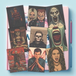 Puede incluir: Una colecci&oacute;n de l&aacute;minas de arte rectangulares con personajes de terror, incluidos Freddy Krueger, Chucky y Tiffany, Valak, Annabelle, Tate Langdon, el logotipo de American Horror Story, Jason Voorhees, Dexter Morgan y una vampiresa.