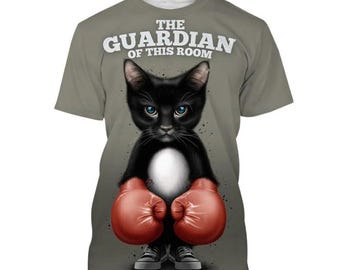 Op de afbeelding: Een grijs T-shirt met een zwarte kat die bokshandschoenen draagt. De kat heeft blauwe ogen en de tekst "The Guardian of This Room" staat op het T-shirt.