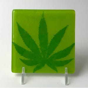 May include: A green glass coaster with a green marijuana leaf design.