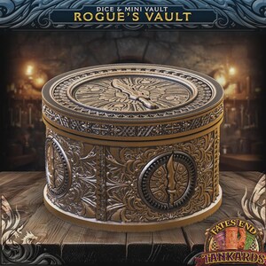 May include: A round, gold-coloured Rogue's Vault dice and mini vault with intricate embossed designs. The lid features a sword design. The vault is on a wooden surface. The text "ROGUE'S VAULT" is at the top.