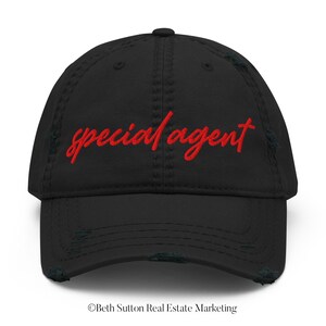 May include: Black distressed baseball cap with red embroidered text that reads "special agent".
