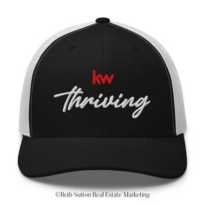 May include: Black and white trucker hat with the text "kw thriving" embroidered in white script. The "kw" logo is red. The hat has a black brim and a white mesh back.