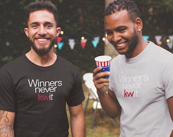 May include: Two people wearing black and gray t-shirts with the text "Winners never quit" in white and red lettering. The person on the left is wearing a black t-shirt and the person on the right is wearing a gray t-shirt.