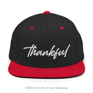 May include: Black and red baseball cap with the word "thankful" embroidered in white on the front.