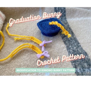 May include: A crochet graduation cap with a yellow tassel and two yellow yarn tails with purple bows. The text "Graduation Bunny Crochet Pattern" is on the image. The text "Modification to Kimono Bunny Pattern" is also on the image.
