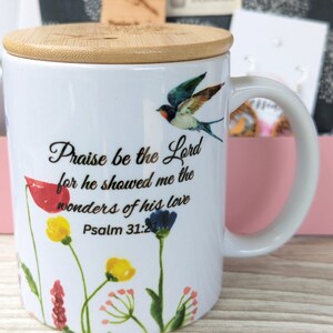Pu&ograve; includere: Tazza in ceramica bianca con coperchio in bamb&ugrave;, con un design floreale e un uccello. La tazza ha una citazione che dice "Lodato sia il Signore perch&eacute; mi ha mostrato le meraviglie del suo amore Salmo 31:21".