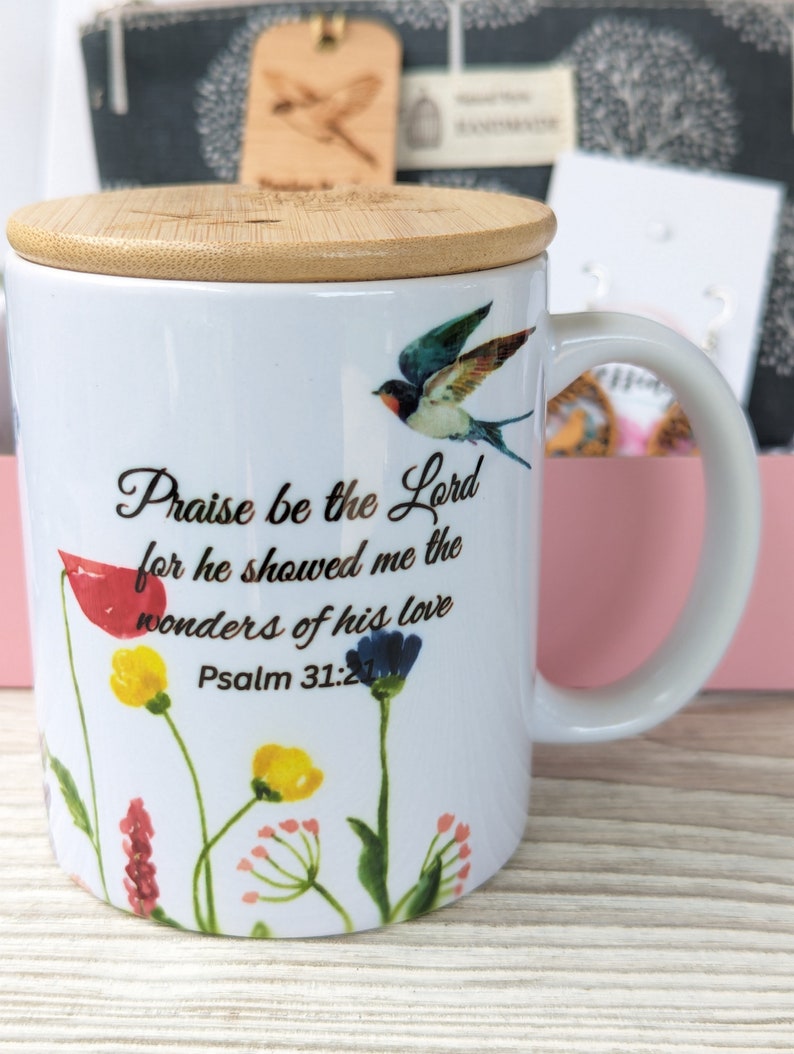 Pu&ograve; includere: Tazza in ceramica bianca con coperchio in bamb&ugrave;, con un design floreale e un uccello. La tazza ha una citazione che dice "Lodato sia il Signore perch&eacute; mi ha mostrato le meraviglie del suo amore Salmo 31:21".
