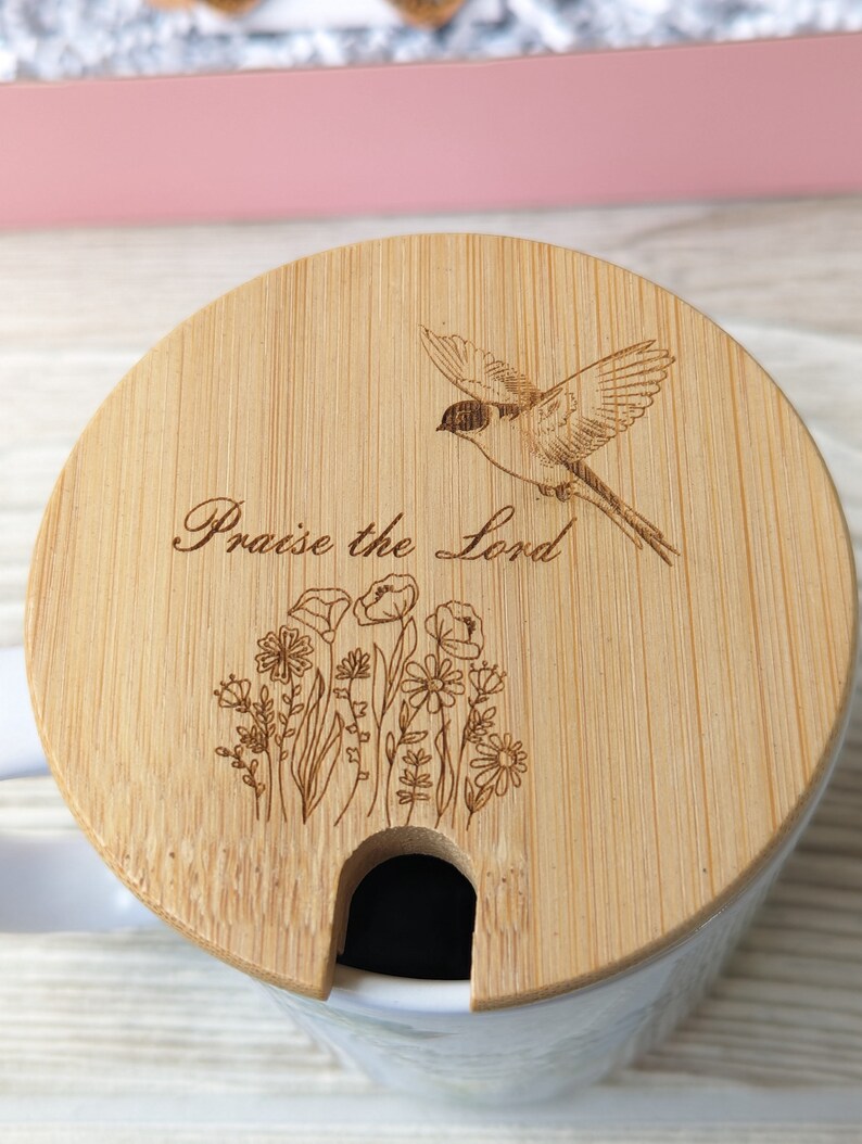 Pu&ograve; includere: Un coperchio per tazza in legno con un design di uccello e fiori. Il coperchio ha un'apertura per una cannuccia e il testo "Praise the Lord" &egrave; inciso sul coperchio.