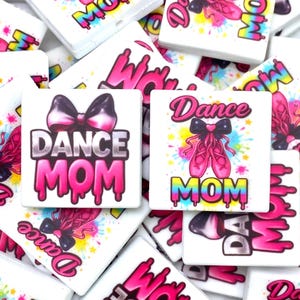 May include: White square tiles with the words "Dance Mom" in pink and black, with a bow and ballet shoes. The tiles are scattered, with a few featuring colorful paint splatters.