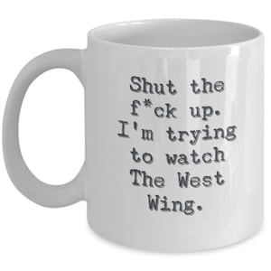 May include: White ceramic coffee mug with a black text design that reads "Shut the f*ck up. I'm trying to watch The West Wing."
