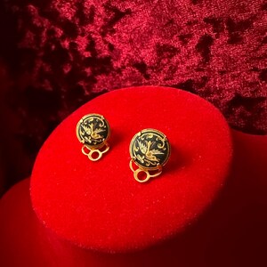May include: A pair of gold-tone clip-on earrings with black enamel and a gold bird design.
