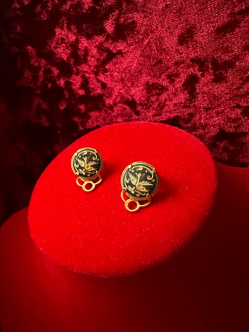 May include: A pair of gold-tone clip-on earrings with black enamel and a gold bird design.