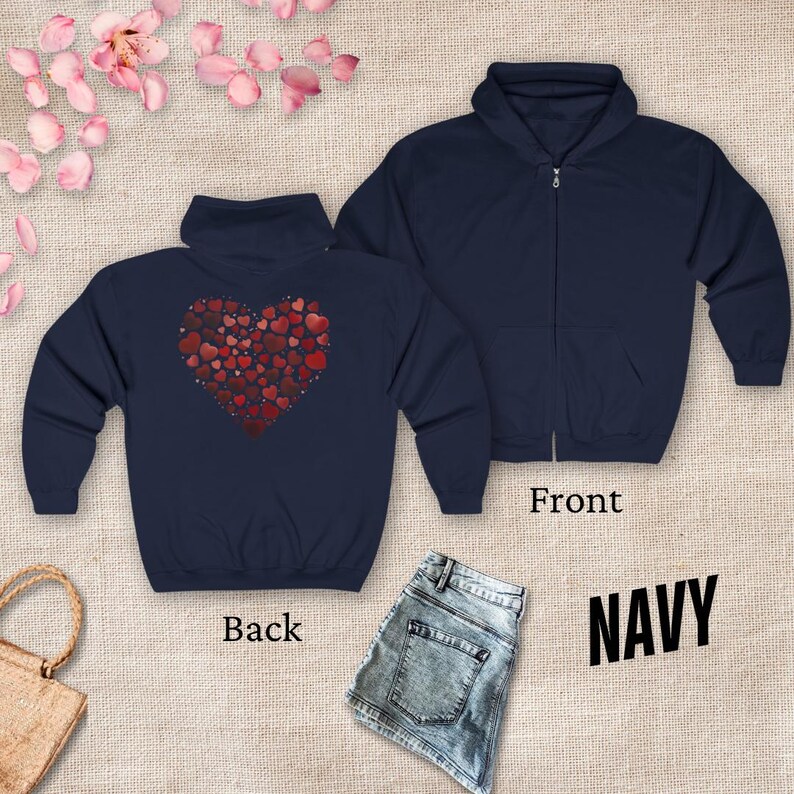 May include: A navy blue zippered hoodie with a red heart design on the back. The heart is made up of many smaller hearts. The hoodie is shown on a model wearing jeans.