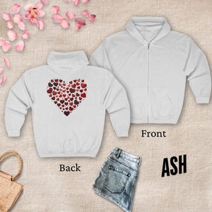 May include: A white zippered hoodie with a heart made of smaller hearts on the back. The front of the hoodie is plain. The hoodie is available in the color ash.