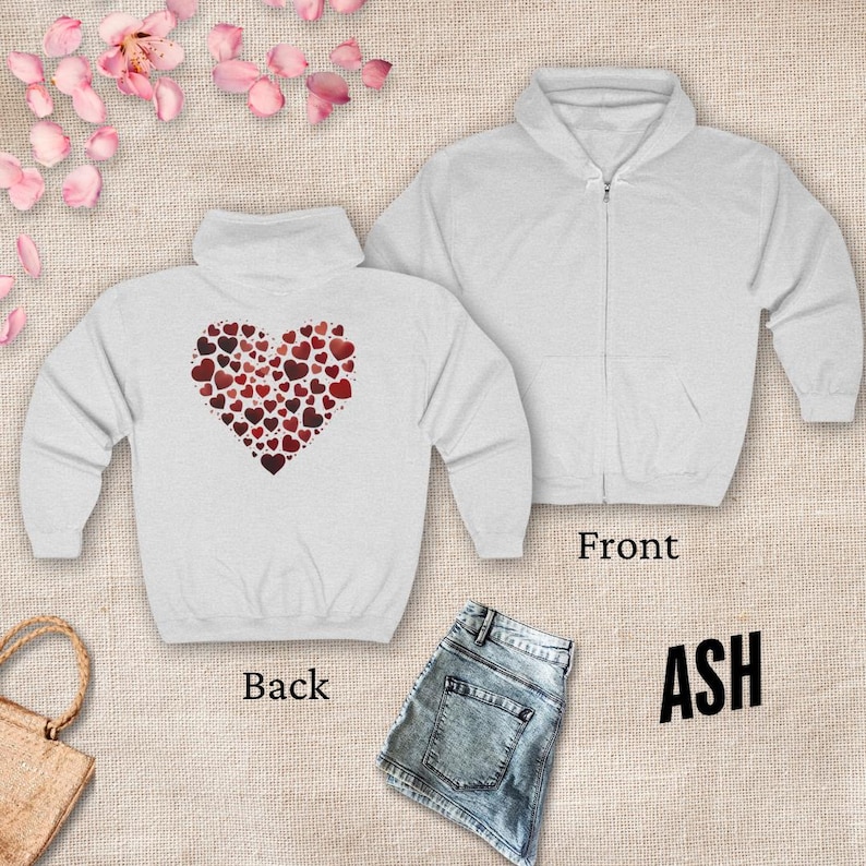 May include: A white zippered hoodie with a heart made of smaller hearts on the back. The front of the hoodie is plain. The hoodie is available in the color ash.