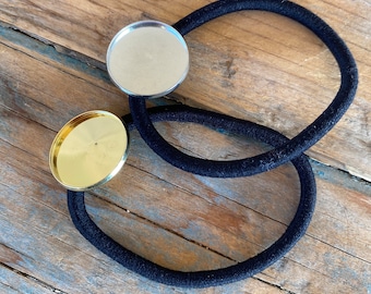 May include: Two black hair ties with round metal embellishments. One embellishment is gold and the other is silver.