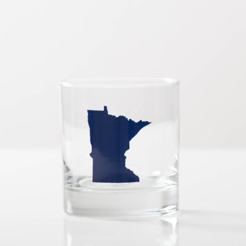 May include: A clear glass tumbler with a blue silhouette of the state of Minnesota.