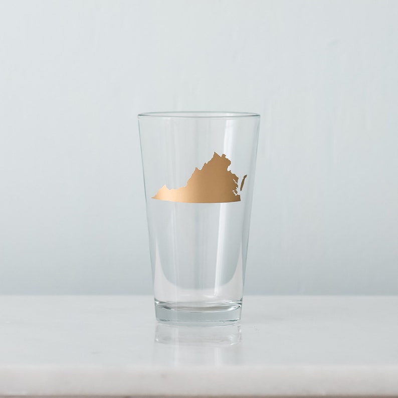 May include: A clear glass pint glass with a gold outline of the state of Virginia.