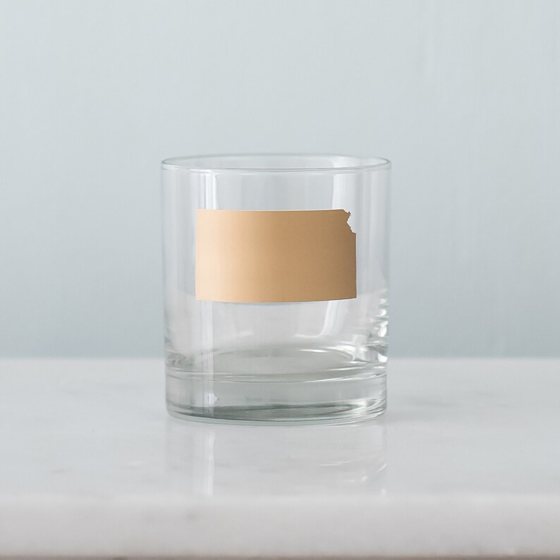 May include: A clear glass tumbler with a gold outline of the state of Kansas.