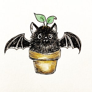 May include: A black bat with green leaves growing out of its head is potted in a brown terracotta pot. The bat has a cute, cartoonish expression.