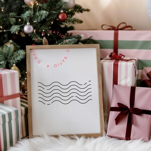May include: A white framed sign with the text "RATIO 4 : 5 RATIO 5 : 4" in a circle. The sign is sitting on a white fluffy surface in front of a Christmas tree and wrapped gifts. The gifts are pink and white striped, pink with burgundy ribbon, and green and pink striped.