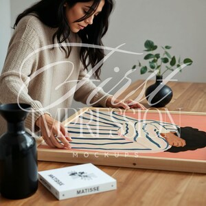 May include: A framed print of a colorful abstract illustration of a person wearing a striped shirt. The print is in a wooden frame and is sitting on a wooden table. The text "First Impression Mockups" is printed on the frame.