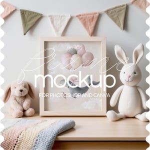 Puede incluir: Una maqueta de marco de madera con fondo blanco y una ilustración de acuarela de una ballena con globos rosas y blancos. El marco está sobre una superficie de madera clara con una manta de punto y un conejito de peluche blanco.