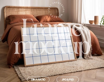 May include: A horizontal frame mockup with a white background and a wooden frame. The frame is sitting on a beige rug in front of a bed with a brown duvet and pillows. The bed is against a white wall with a window in the background.