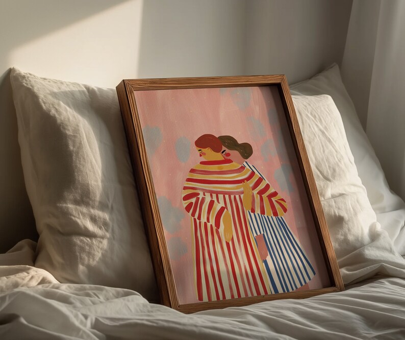 May include: A framed illustration of two people standing side-by-side. The person on the left is wearing a red and white striped dress. The person on the right is wearing a blue and white striped dress. The background is a light pink color with white dots.