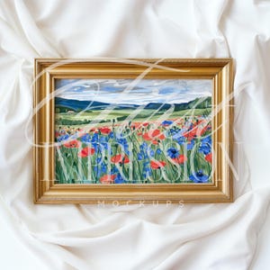Puede incluir: Una pintura enmarcada que representa un campo de flores azules y rojas con un paisaje distante en el fondo. El marco es dorado y tiene un dise&ntilde;o simple.
