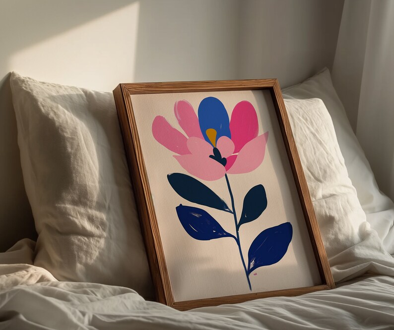 May include: A framed print of a stylized pink, blue, and white flower with green leaves on a white background.