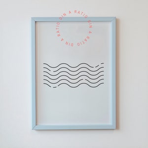 May include: A light blue framed print with a black and white wave design. The text "DIN A RATIO DIN A RATIO" is written in a circle around the center of the print.