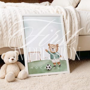 May include: A watercolor illustration of a brown bear wearing a green and white soccer uniform, kicking a soccer ball. The bear is standing on a green field with a white goal in the background. The illustration is framed in a white frame and is sitting on a white fluffy rug.