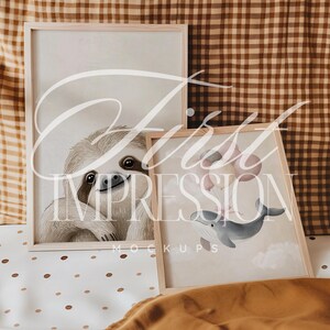 May include: Two framed illustrations, one with a sloth and the other with a whale holding balloons. The frames are light wood and the illustrations are on a cream background.