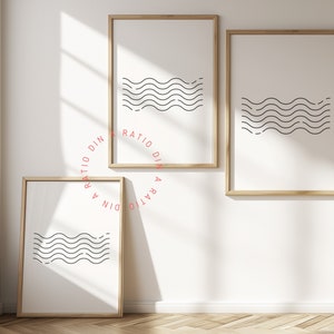 以下が含まれることがあります： ミニマリストデザインの額入りアートプリント3点。各プリントは、白地の背景に黒い波線が並んでおり、薄茶色の木製フレームに収められています。アートワークは白い壁に展示され、自然光が差し込んでいます。