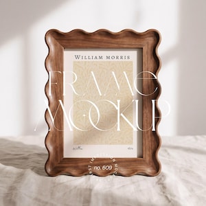 Peut inclure: Un cadre photo en bois avec un bord ondulé, affichant une impression avec le texte "WILLIAM MORRIS" et "FRAME MOCKUP". L'impression présente un motif floral beige et le mot "Willow". Le cadre est posé sur une surface de couleur neutre.