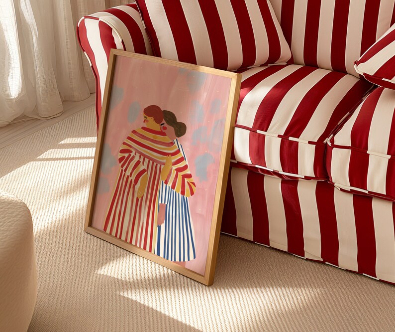 Puede incluir: Una impresi&oacute;n art&iacute;stica enmarcada que representa a dos figuras abraz&aacute;ndose, renderizada en un estilo suave y pict&oacute;rico. La obra de arte muestra figuras con ropa a rayas sobre un fondo rosa con acentos azul claro. El marco es de color madera clara.