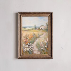 Op de afbeelding: Een ingelijst olieverfschilderij dat een wit huisje in een veld vol wilde bloemen toont. Het pad naar het huisje is bezaaid met kleurrijke bloemen en de achtergrond toont een glooiend groen landschap.