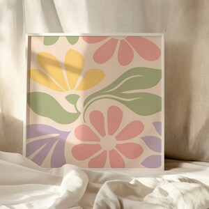 May include: A framed print with a colorful abstract floral design. The print features pink, yellow, green, and purple flowers on a light beige background.