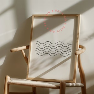 May include: A framed print with a minimalist design of wavy lines in black on a white background. The frame is made of natural wood and the print has the text "DIN A RATIO DIN A RATIO" in a pink circle.