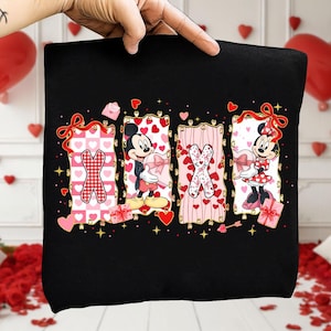 May include: Black Valentine's Day themed graphic featuring the letters XOXO with Mickey and Minnie Mouse. The letters are decorated with hearts and bows. Mickey and Minnie are holding gifts. The background is decorated with hearts and stars.